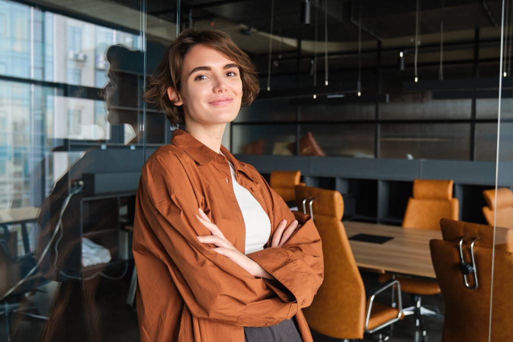 Professionnelle dans un espace de travail collaboratif adjacent à une salle de réunion. Les emplois en assurance au Québec valorisent la collaboration et le développement des compétences.
