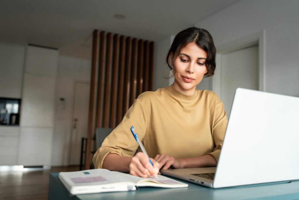 Professionnelle prenant des notes devant un ordinateur portable dans un espace de travail. La formation continue fait partie des carrières en assurance au Québec.