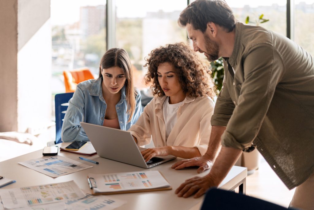 Équipe de PME discutant de risques informatiques autour d’un ordinateur portable.